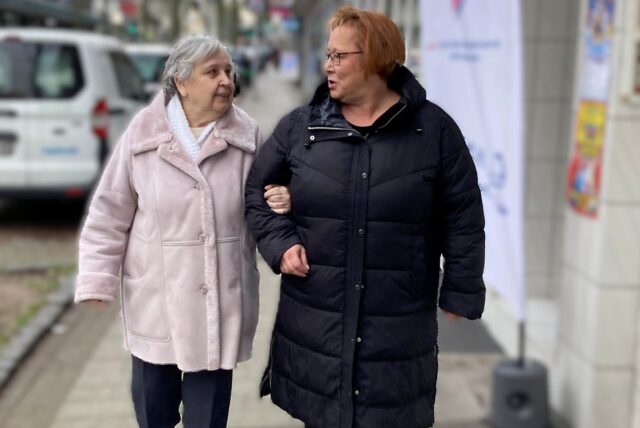 Inge Müller (links) hat sich bei Martina Lotz eingehakt. Beide Frauen schauen sich beim Bummel über die Bahnhofstraße in Herten-Westerholt an und unterhalten sich.
