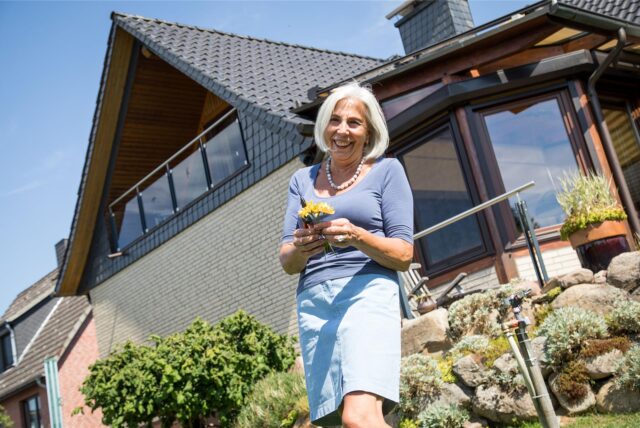 Seniorin mit Blumen im Garten ihre Eigenheims.