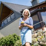 Seniorin mit Blumen im Garten ihre Eigenheims.
