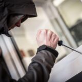 Eine Person hebelt mit einem Schraubendreher ein Fenster auf.