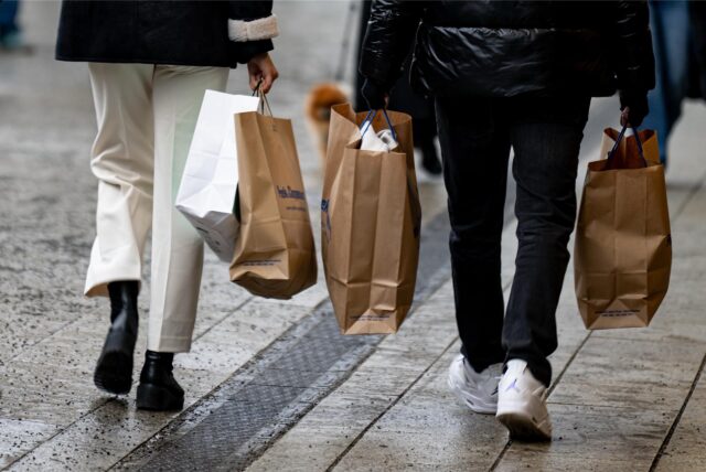 Menschen gehen mit Einkaufstüten am verkaufsoffenen Sonntag durch die Innenstadt.