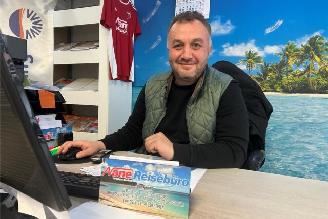Erhan Nane lächelt an seinem Schreibtisch.
