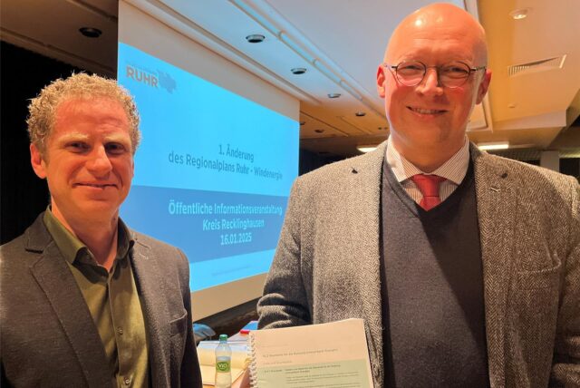 Stefan Kuczera und Markus Gerber vom RVR lächeln vor dem Hintergrund von Planungsunterlagen in die Kamera.