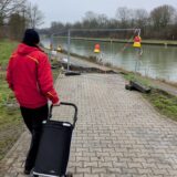En Mann mit Einkaufstrolley steht vor einer Baustellen-Absperrung.