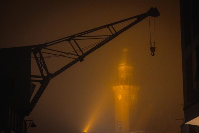 Ein Hafenkran umgeben von dichtem Nebel.