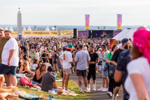 Zahlreiche Besucherinnen und Besucher stehen beim Sunset Picknick 2024 auf dem Sonnenuhr-Plateau der Halde Hoheward in Herten.