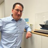 Michael Germann steht in seinem Reisebüro in Herten-Disteln neben dem Modell eines Kreuzfahrtschiffes.