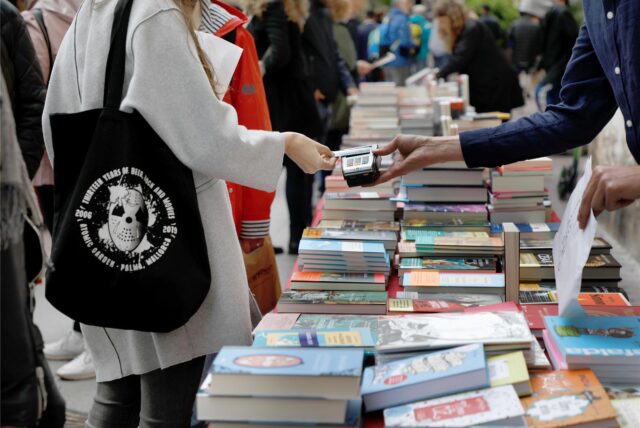 Passanten stöbern auf der Straße an einem Stand in Büchern