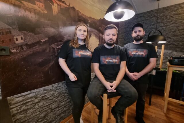 Drei Personen stehen vor einem Wandbild.