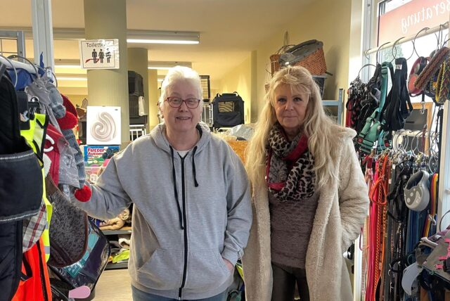 Zwei Tierretter der Arche 90 stehen vor dem Hundezubehör des second-Pfoten Shops.