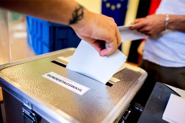 Ein Wähler wirft in einem Wahllokal seinen Stimmzettel für die Bundestagswahl in eine Wahlurne.