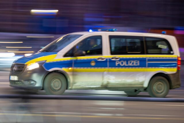 Das Bild zeigt ein komplettes Polizeiauto, das schnell die Straße entlang fährt.