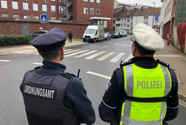Ein Polizist und ein Mitarbeiter des Ordnungsamtes vor dem Drogenkonsumraum in Dortmund