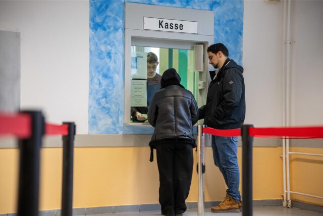 Zwei Menschen stehen an einem Kassenschalter.