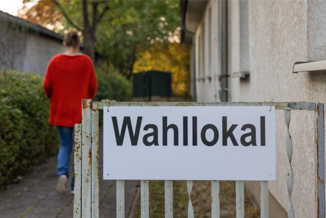 Eine Wahlhelferin läuft in ein Wahllokal.