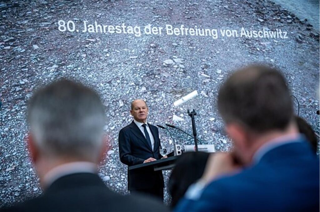 Olaf Scholz hält eine Rede. Auf der Leinwand hinter ihm auf der Bühne steht: 80. Jahrestag der Befreiung von Auschwitz. Olaf Scholz hält eine Rede. Auf der Leinwand hinter ihm auf der Bühne steht: 80. Jahrestag der Befreiung von Auschwitz.