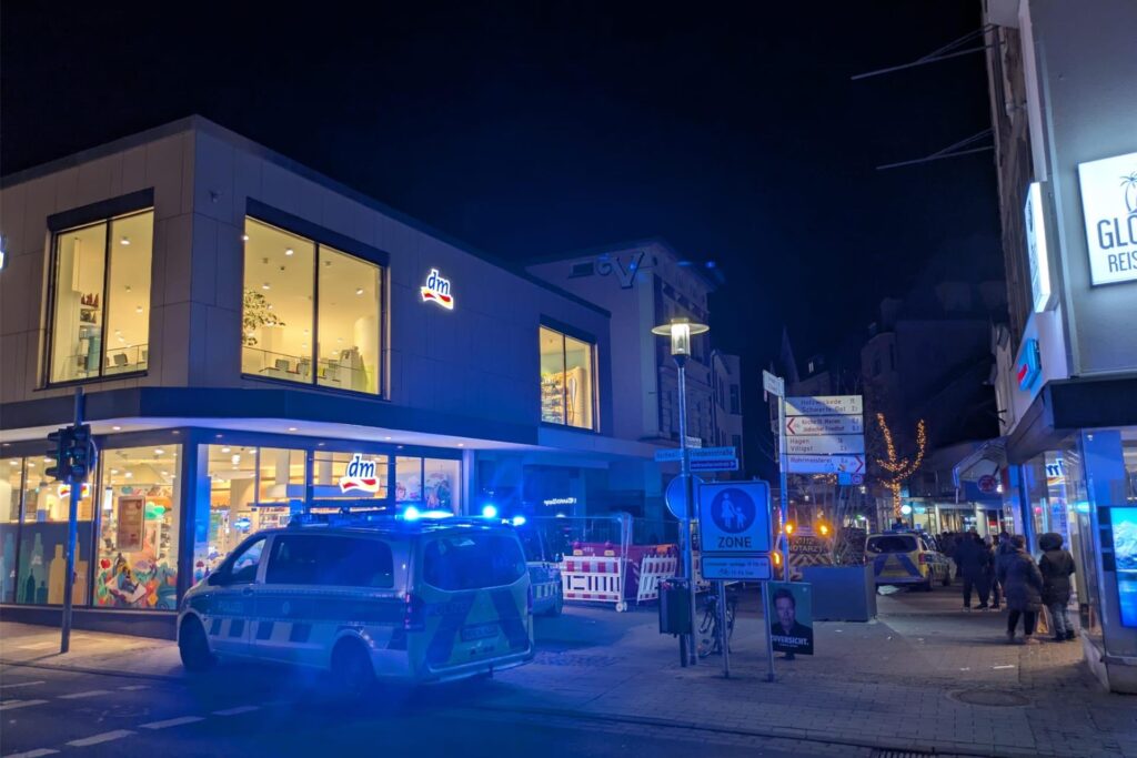 Ein Polizeiwagen steht vor dem dm-Drogeriemarkt in Schwerte. Im Hintergrund sind weitere Fahrzeuge zu sehen.