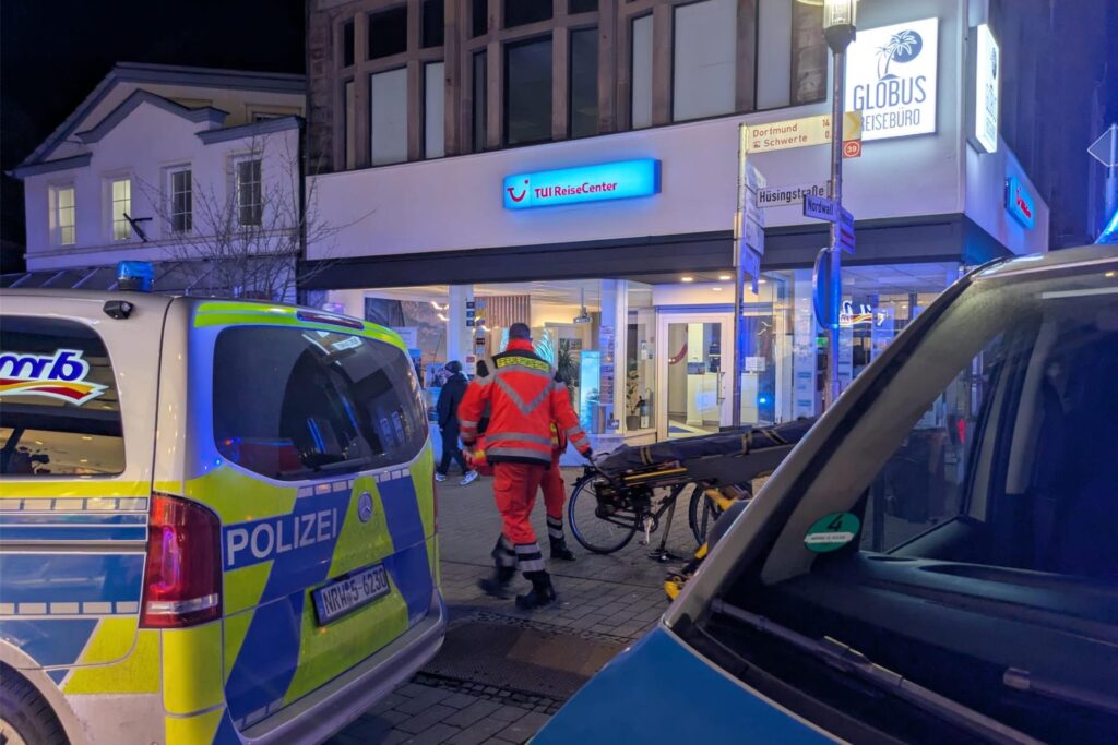 Rettungskräfte laufen vor dem Tui-Reisecenter in Schwerte her. Im Vordergrund sind Polizeiwagen zu sehen.