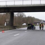 Bremsspuren auf der linken Fahrbahn, ein Warndreieck und das stehengebliebene Auto mit Einsatzkräften der Feuerwehr auf der A 42.