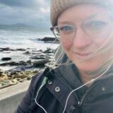 Selfie von Mareike Graepel am Strand mit unruhigem Meer im Hintergrund