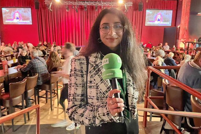 Rosi Taslima Azam steht im Revuepalast mit Mikro in der Hand.