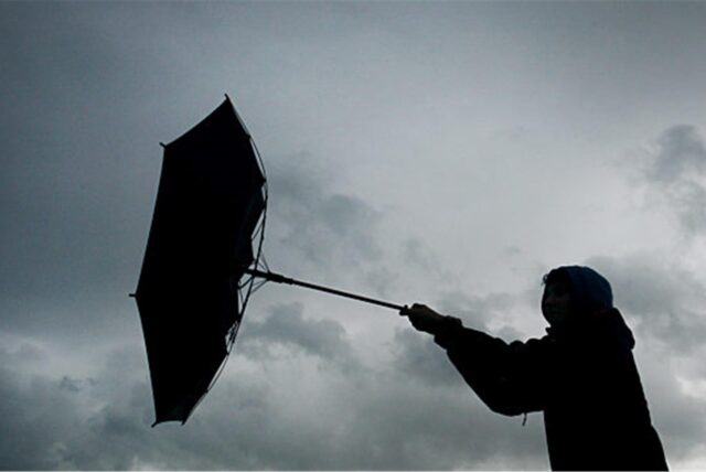 Von einer Windböe erfasst wird der Regenschirm eines Spaziergängers.
