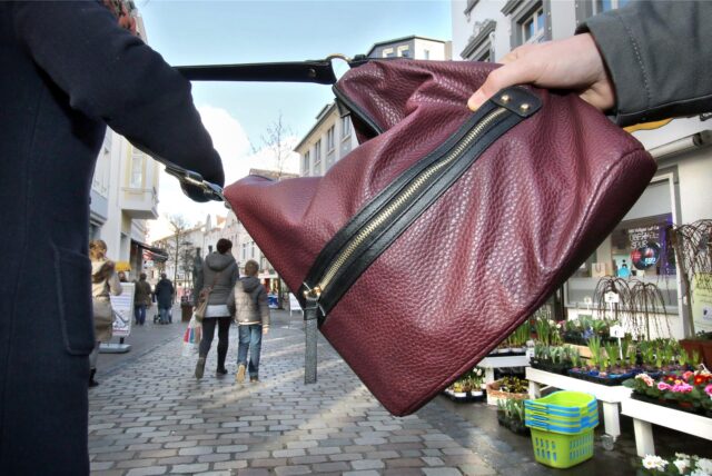 Ein Mann reißt einer Frau die Handtasche vom Arm.