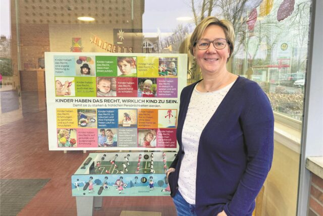Andrea Wiesmann vor einem Kinderrechte-Plakat an der Kita St. Ludgerus.