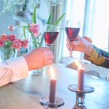 Ein Paar stößt an einem für Valentinstag dekorierten Tisch mit Rotwein an.