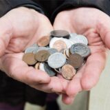 Kundin steht mit einer Handvoll D-Mark-Stücken und Pfennigen