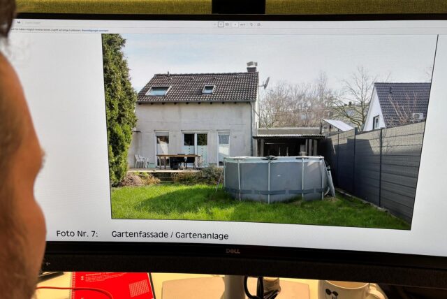 RZ-Redakteur Tobias Mühlenschulte blickt auf einen Monitor, der eine Gartenansicht eines Einfamilienhauses in Recklinghausen zeigt, das am Amtsgericht Recklinghausen im März 2025 zwangsversteigert werden soll.