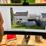 RZ-Redakteur Tobias Mühlenschulte blickt auf einen Monitor, der eine Gartenansicht eines Einfamilienhauses in Recklinghausen zeigt, das am Amtsgericht Recklinghausen im März 2025 zwangsversteigert werden soll.