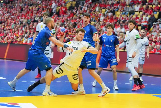 Johannes Golla setzt sich im Spiel der Handball-WM 2025 gegen Italien gegen zwei Verteidiger durch.