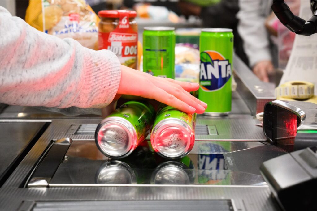 Eine Kassiererin scannt Fanta-Getränkedosen an der Kasse eines Supermarktes.