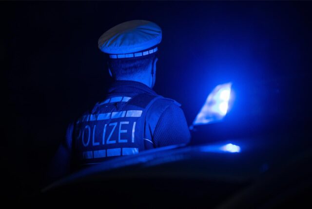 Ein Polizist im Dunkeln neben einem Blaulicht