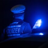 Ein Polizist im Dunkeln neben einem Blaulicht