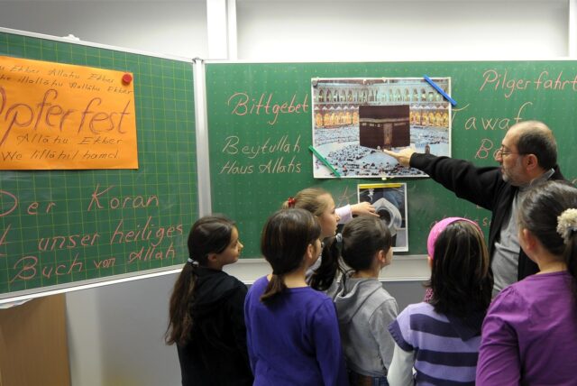 Lehrer und Kinder vor einer Tafel beim Islamunterricht.