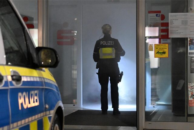 Polizistin steht im Eingang der von Nebel erfüllten Sparkassen-Filiale.