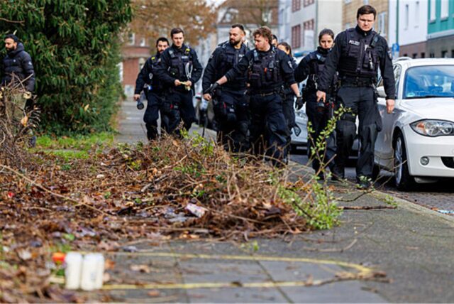 Polizisten einer Einsatzhundertschaft durchsuchen das Umfeld des Tatorts, wo ein Mann bei einem gewaltsamen Angriff in Duisburg durch Schüsse getötet worden sein soll.