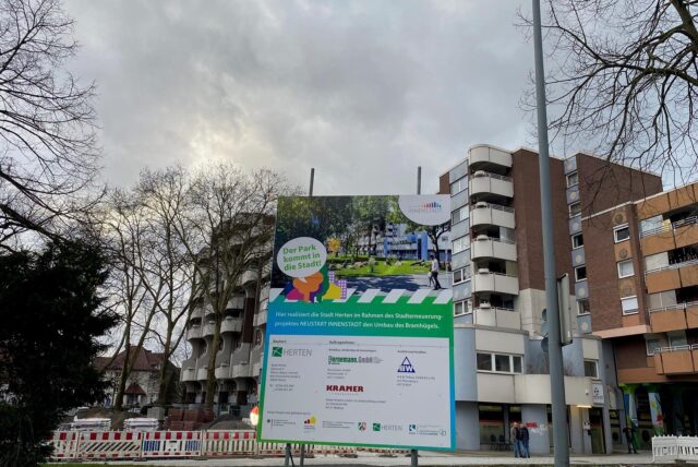 Ein Bauschild mit dem Slogan „Der Park kommt in die Stadt“ steht an der Baustelle am Bramhügel in Herten.