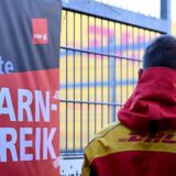 Streikposter am Werkstor: Ein DHL-Mitarbeiter hat die Arbeit niedergelegt und schaut auf eine Zustellbasis, in der er sonst arbeitet.