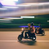 Zwei Personen fahren auf einem Roller.