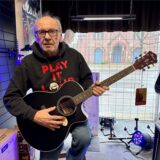 Karl-Heinz Brawand hält eine Gitarre in den Händen.