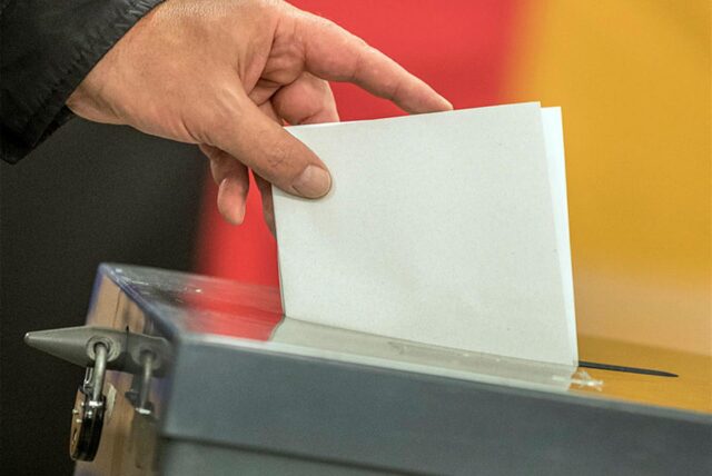 Ein Mann wirft einen Wahlzettel in eine Wahlurne