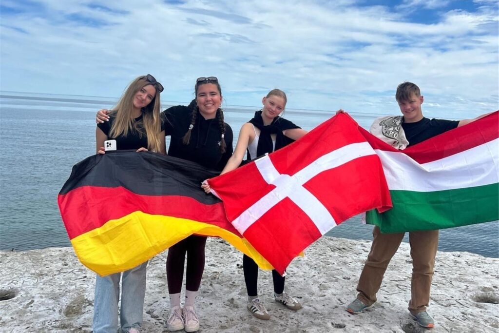 Lilli und weitere Austauschschüler auf einem Felsen in Puerto Madryn: Sie halten die Landesflaggen von Deutschland Dänemark und Ungarn. Lilli und weitere Austauschschüler auf einem Felsen in Puerto Madryn: Sie halten die Landesflaggen von Deutschland Dänemark und Ungarn.