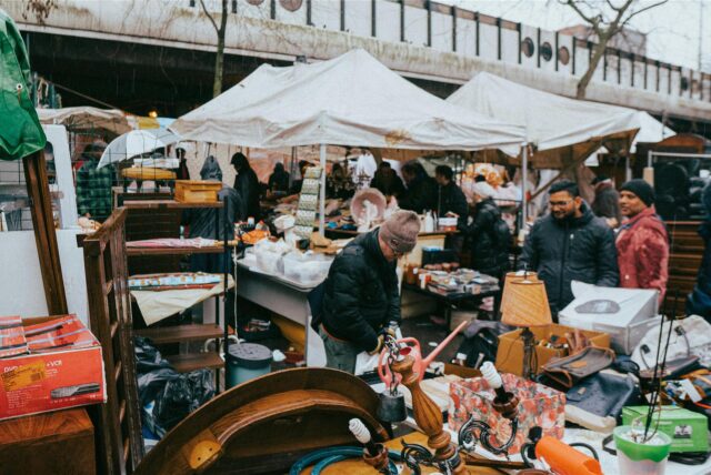 Menschen durchstöbern verschiedene Stände mit Gebrauchtgegenständen auf einem Trödelmarkt.
