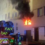 Einsatzkräfte der Feuerwehr Dortmund löschen ein Feuer, dichter Rauch kommt aus der Brandwohnung.