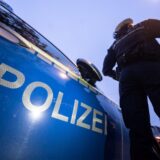 Eine Polizistin steht neben einem Polizeifahrzeug.