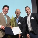 Bürgermeister Rajko Kravanja (links) und Redaktionsleiter Fabian Hollenhorst (rechts) würdigen Marc Frese mit der Verleihung der Ehrennadel.