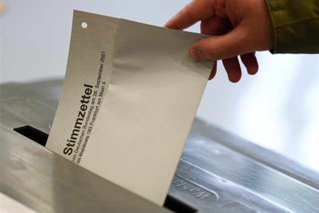 Ein Mann steckt im Wahllokal seinen Stimmzettel für die Bundestagswahl in eine Wahlurne.